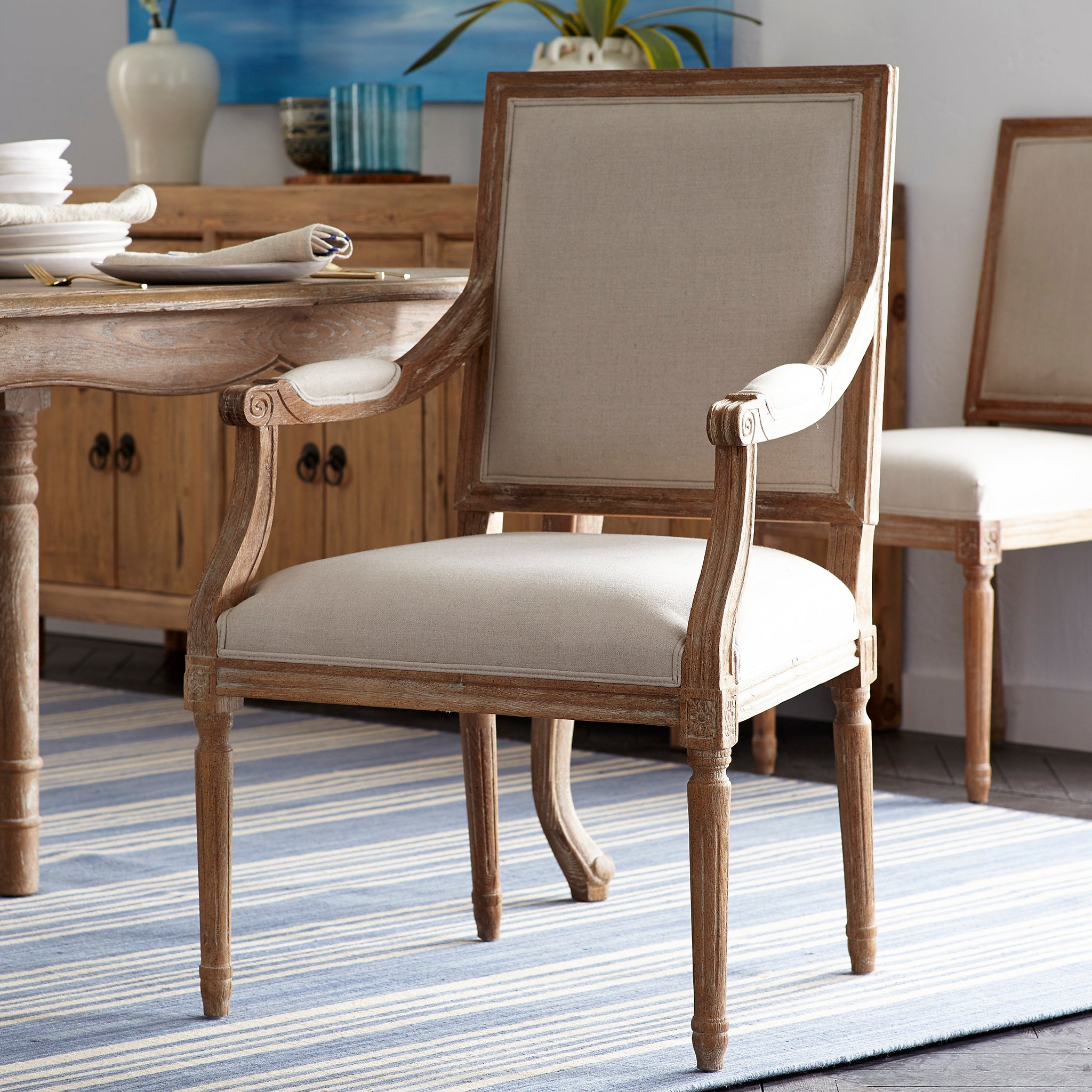 Chateau Chair With Arm – natural linen, weathered wood, styled in dining room with rustic table.