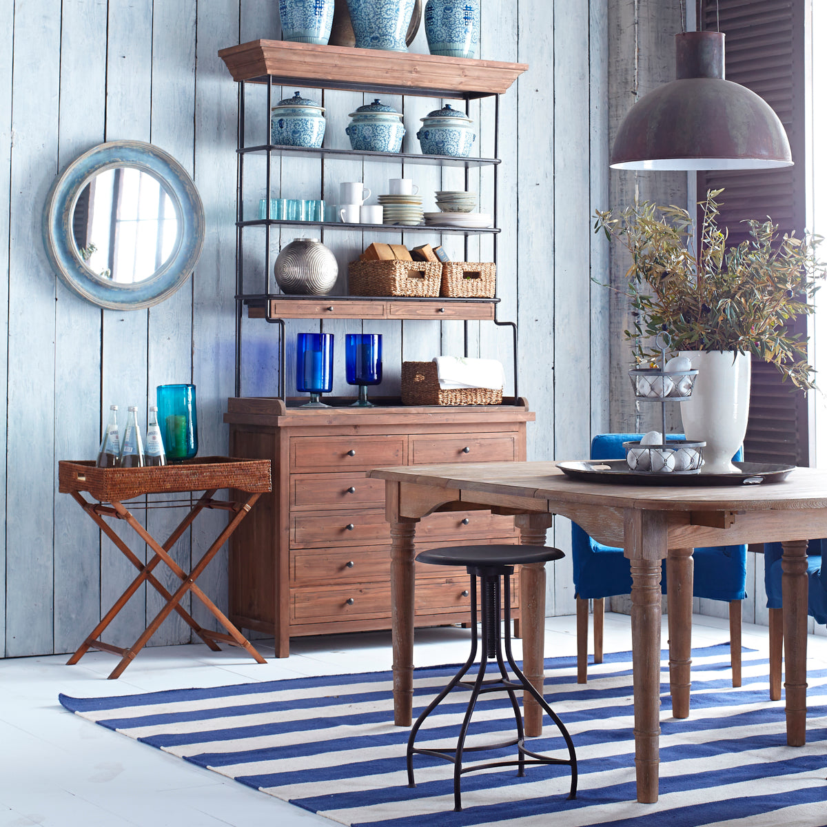 Expandable Oak Farmhouse Table – Rustic dining space, wooden hutch, striped rug, decorative setup.