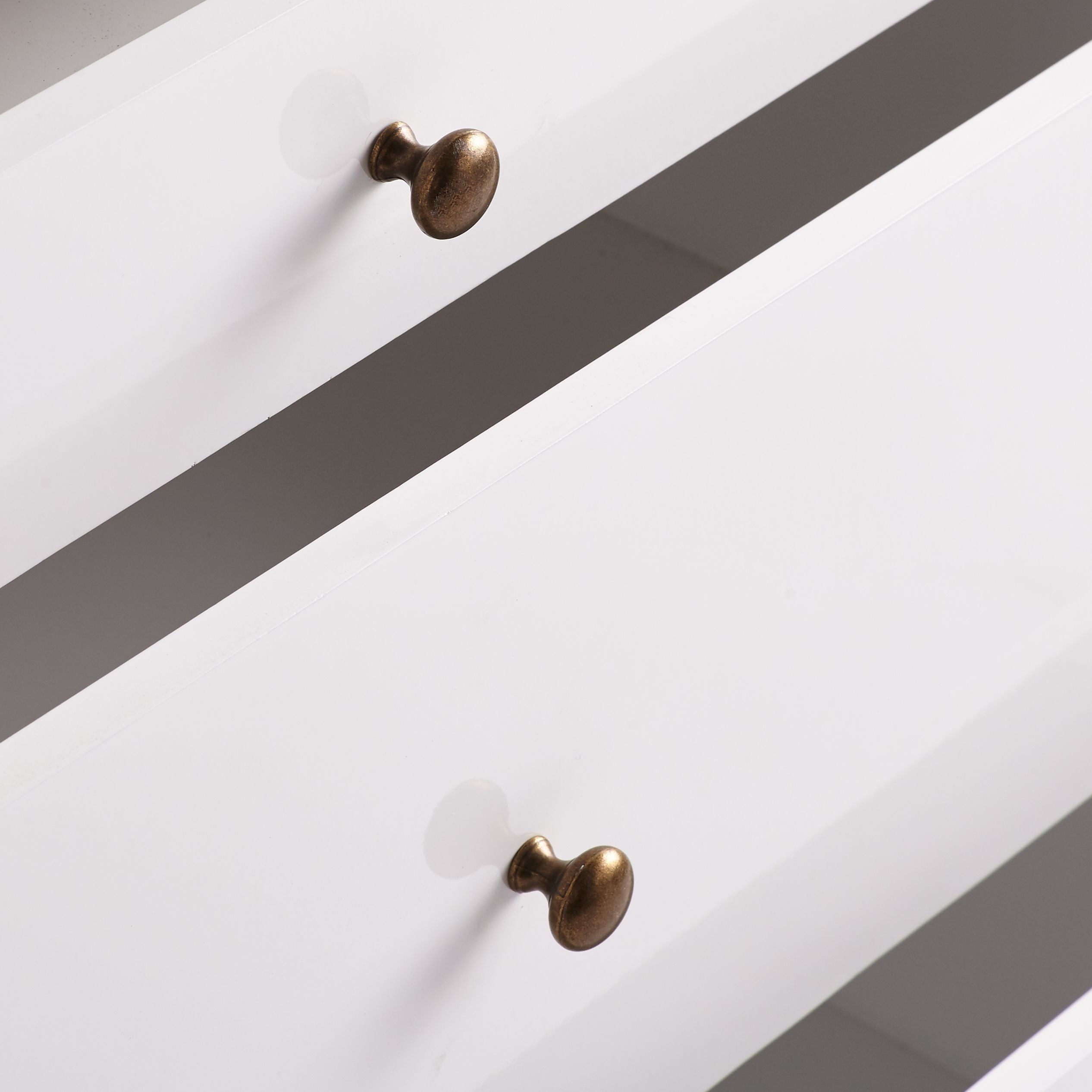 Small Sleek Chest - Close-up of white drawers with brass knobs.