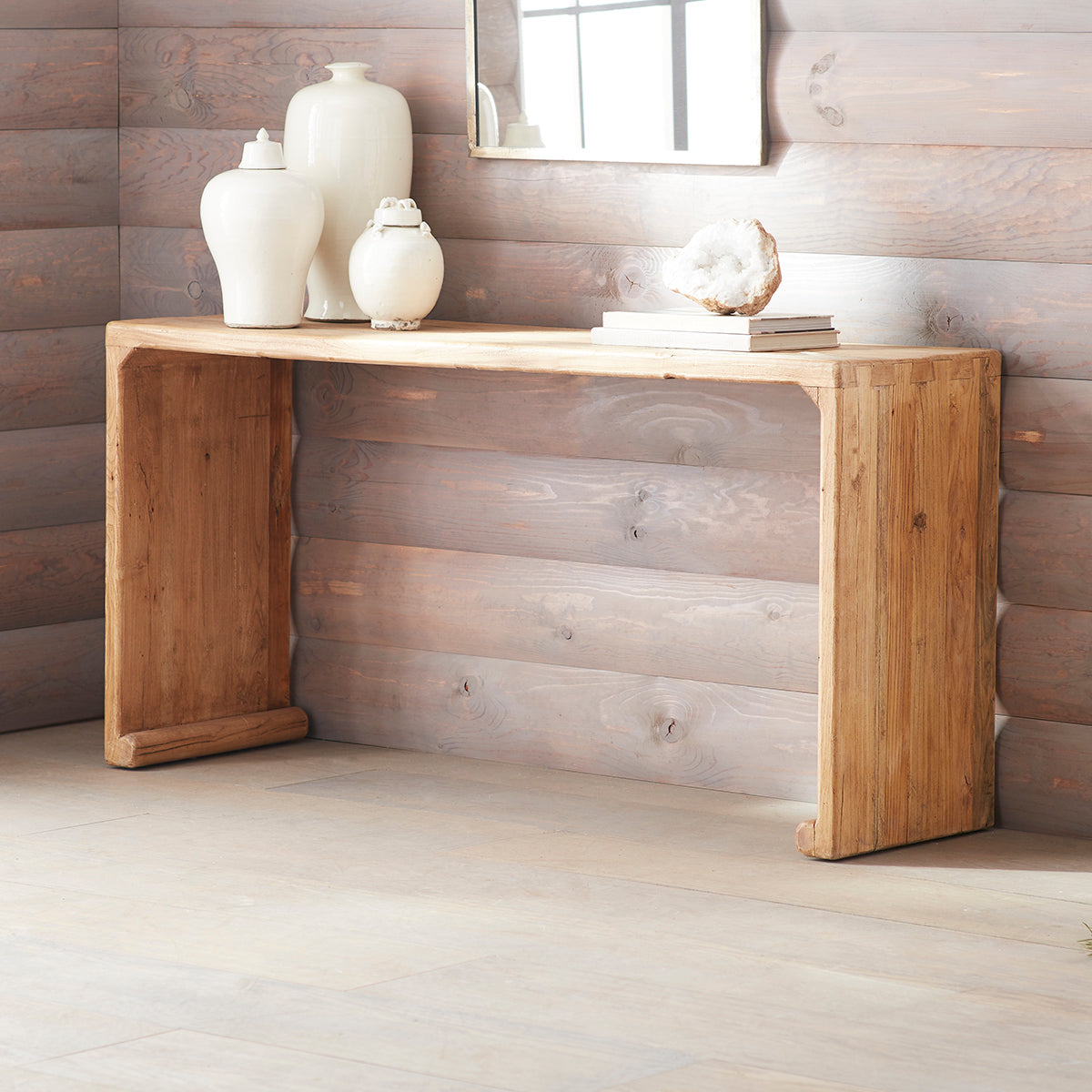 Rustic Console Table – Against a wood-paneled wall, decorated with white vases.