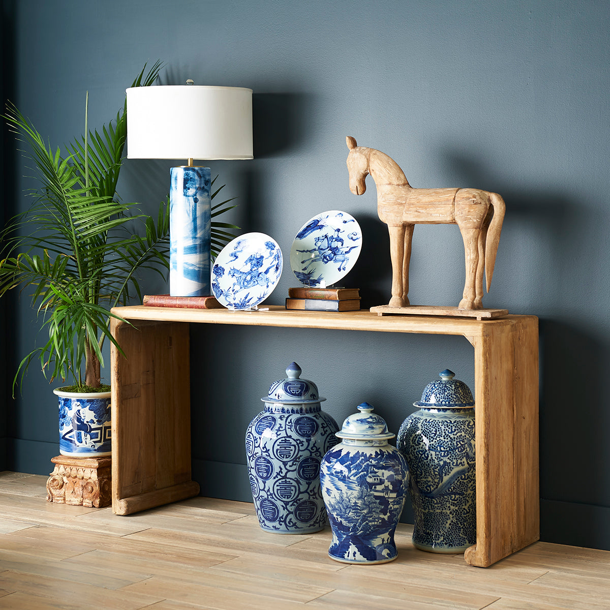 Rustic Console Table – Styled with blue porcelain, books, lamp, wooden horse.
